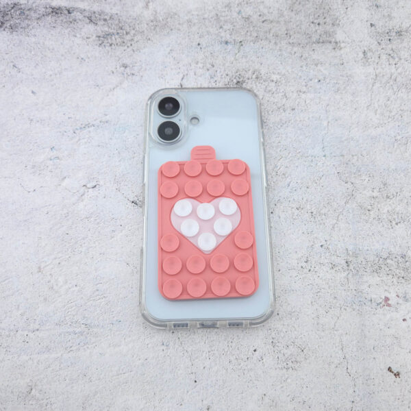 Noppie-Heart-Patch in Peach mit weißem Herz als Smartphone-Halterung auf transparenter Handyhülle, sicher haftend für Fotos und Videos